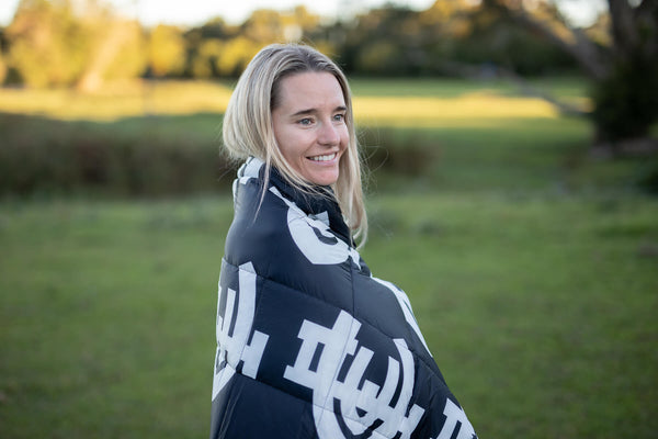 Carlton Blues navy and white puffy blanket worn as a wrap outdoors, featuring geometric logo design