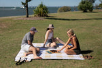 Image of three people sitting in Nakie's recycled picnic blanket, enjoying their snacks while embracing sustainability in the outdoors. preview #15