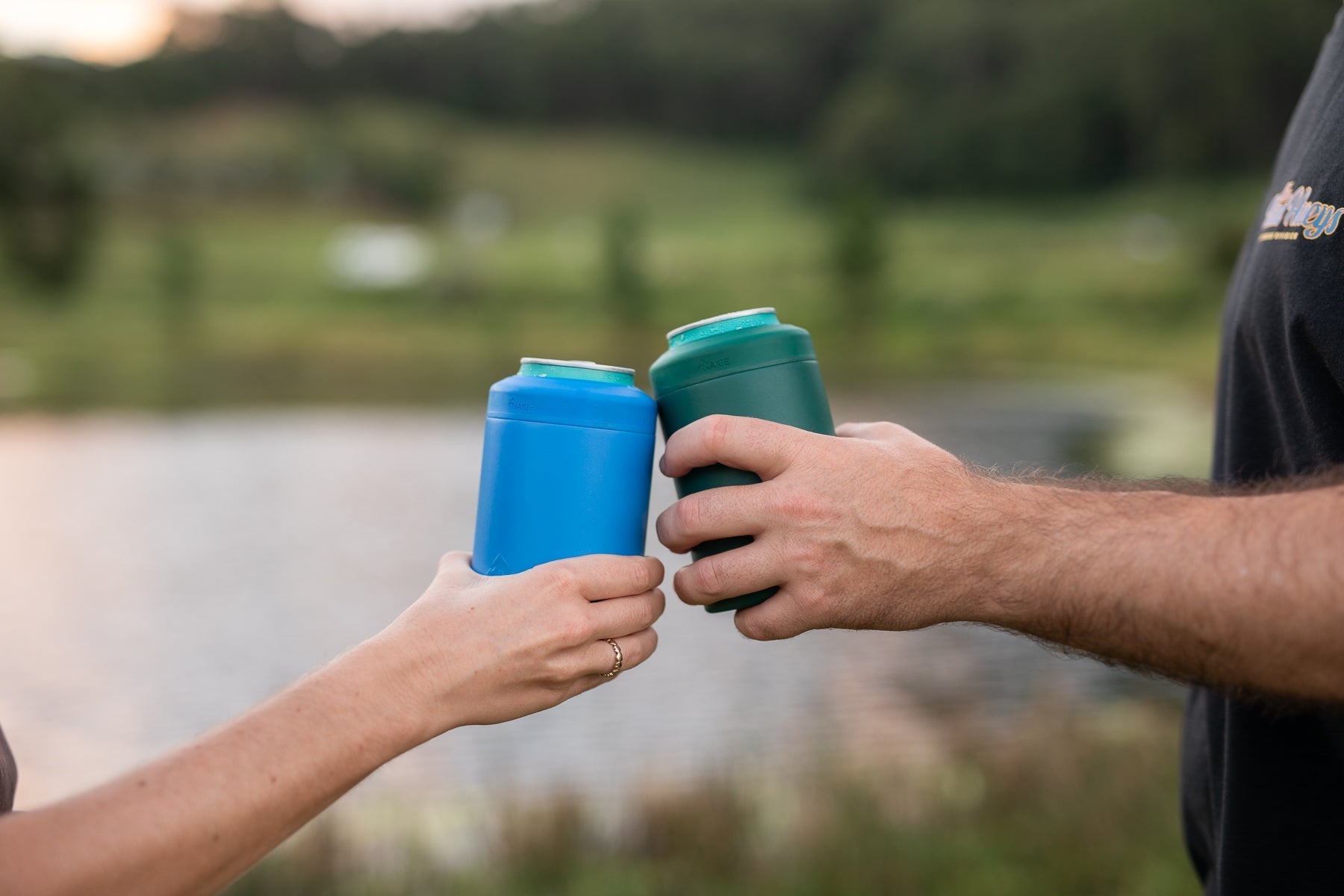 Two people holding Nakie Cooler Cups outdoors.