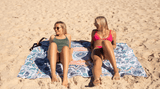 Two women relaxing on a Nakie XL beach towel Nakie
