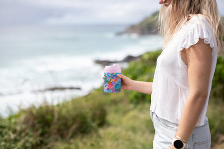 Kasey Rainbow Cooler & Coffee Cup held on a coastal clifftop