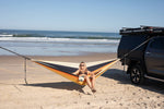 Recycled hammock with yellow, navy, and cream stripes, suspended between vehicle and beach pole. preview #5