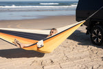 Portable hammock with yellow and orange nylon straps suspended between vehicle and ground on beach preview #6