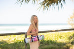 Recycled picnic blanket with multicolored watercolor print, rolled with black straps, carried by woman at beach preview #11