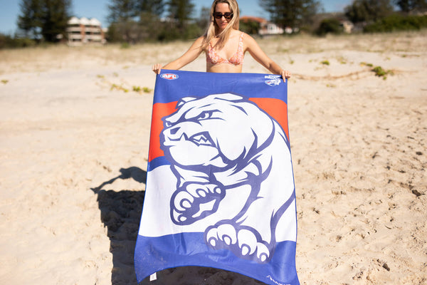 Western Bulldogs AFL beach towel in blue and orange with white bulldog logo, sand-free microfiber material, displayed on beac
