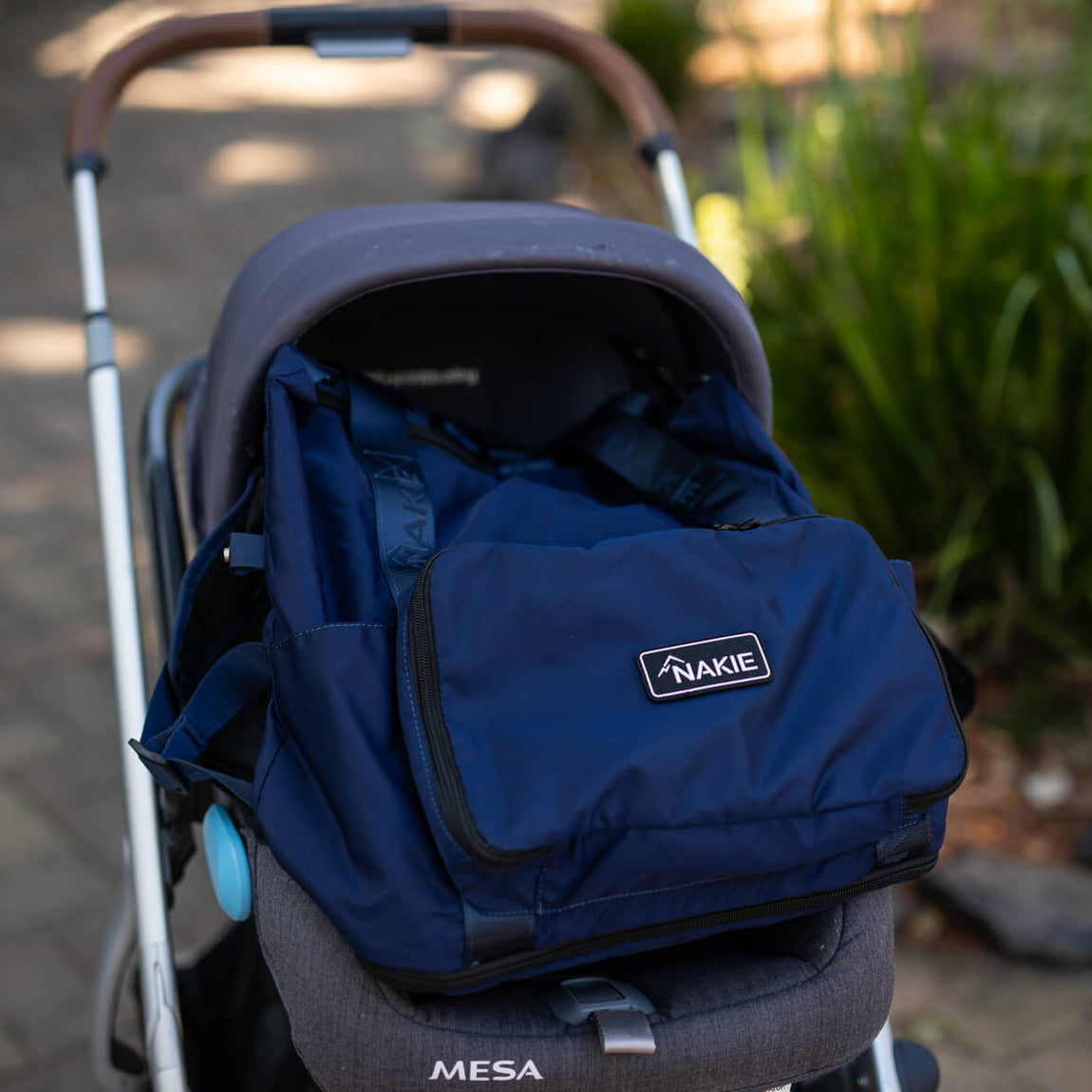 Navy recycled tote bag with Nakie branding, attached to stroller seat in front-facing view