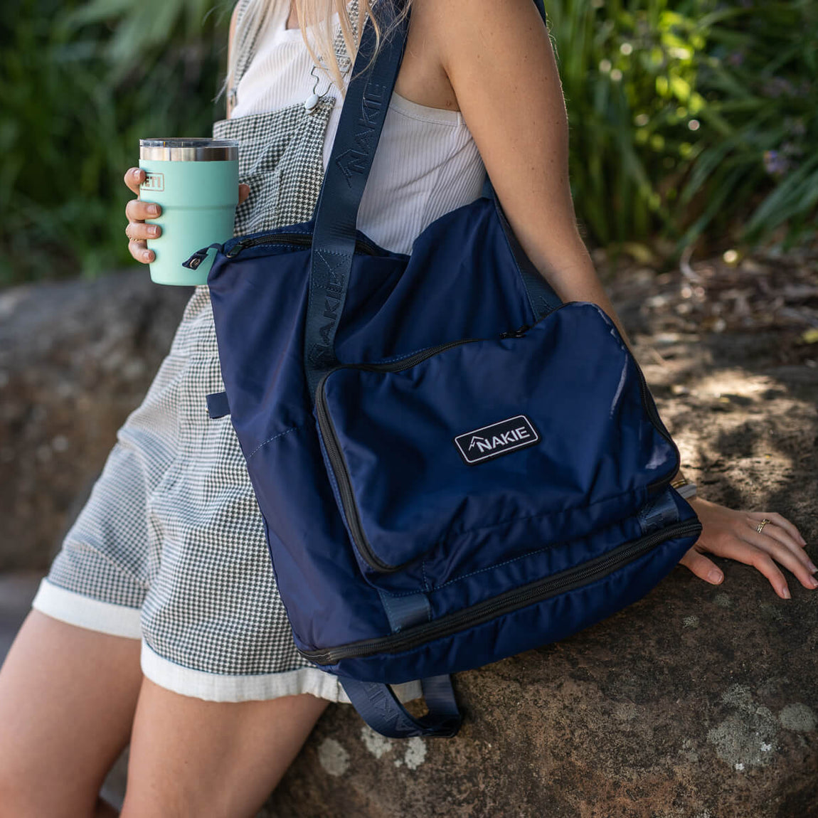Navy recycled tote bag with branded patch, worn cross-body outdoors