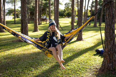 Person sitting in a Nakie NRL Cowboys hammock with trees in the background
