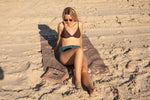 Brown recycled sand-free beach towel with leaf pattern, displayed on sand at beach with woman sitting on it preview #15