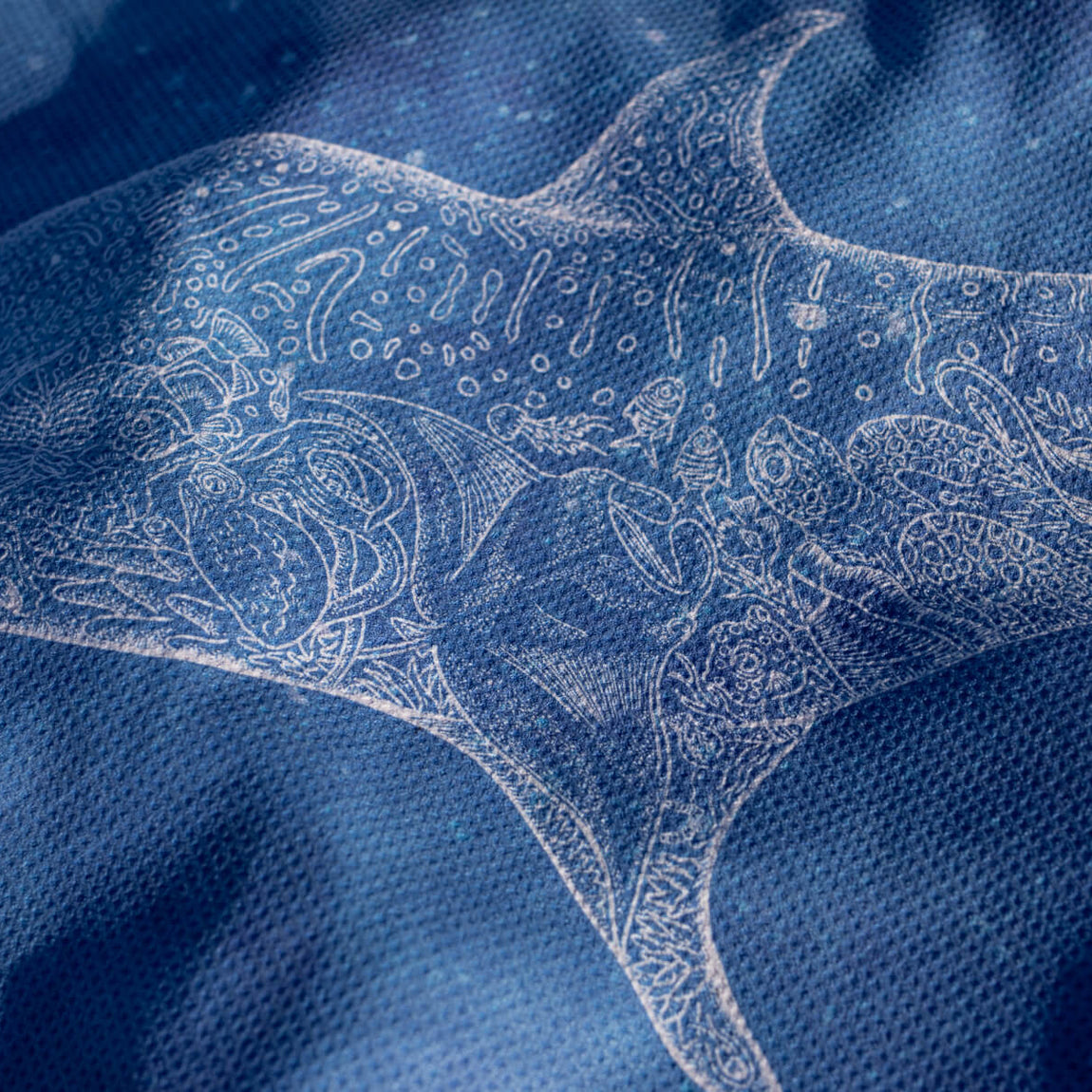 Blue beach towel with intricate white embroidered manta ray and ocean-inspired pattern design