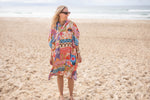 Colorful hooded towel with retro beach-inspired geometric print in red, blue, orange and purple, worn on beach. preview #11