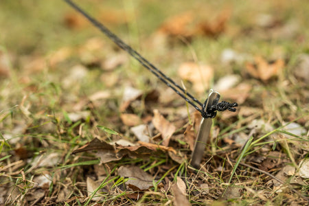 Stainless steel pegs securing the rope for Nakie's Bug Net & Rain Tarp Combo, ensuring stability and durability for outdoor adventures.