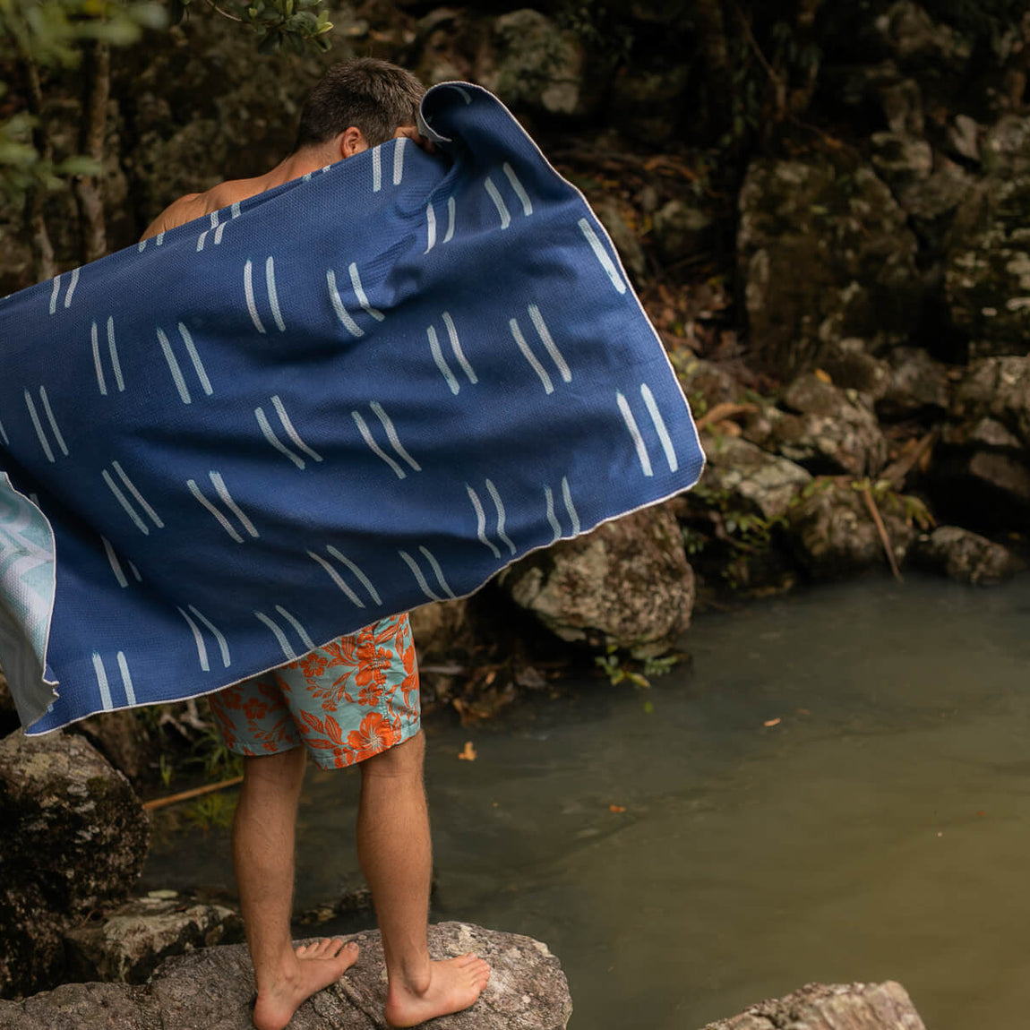 Navy beach towel with white geometric dash pattern, shown on child by water's edge